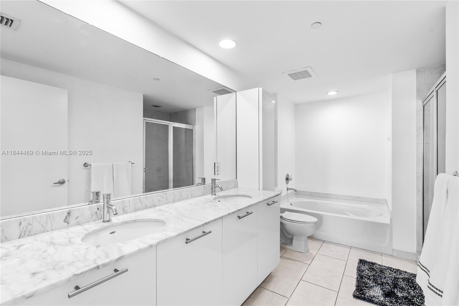 951 Brickell Avenue, Unit 1505 Miami, FL 33131 - Photo 27 of 48 a bathroom with a double vanity sink toilet mirror and bathtub