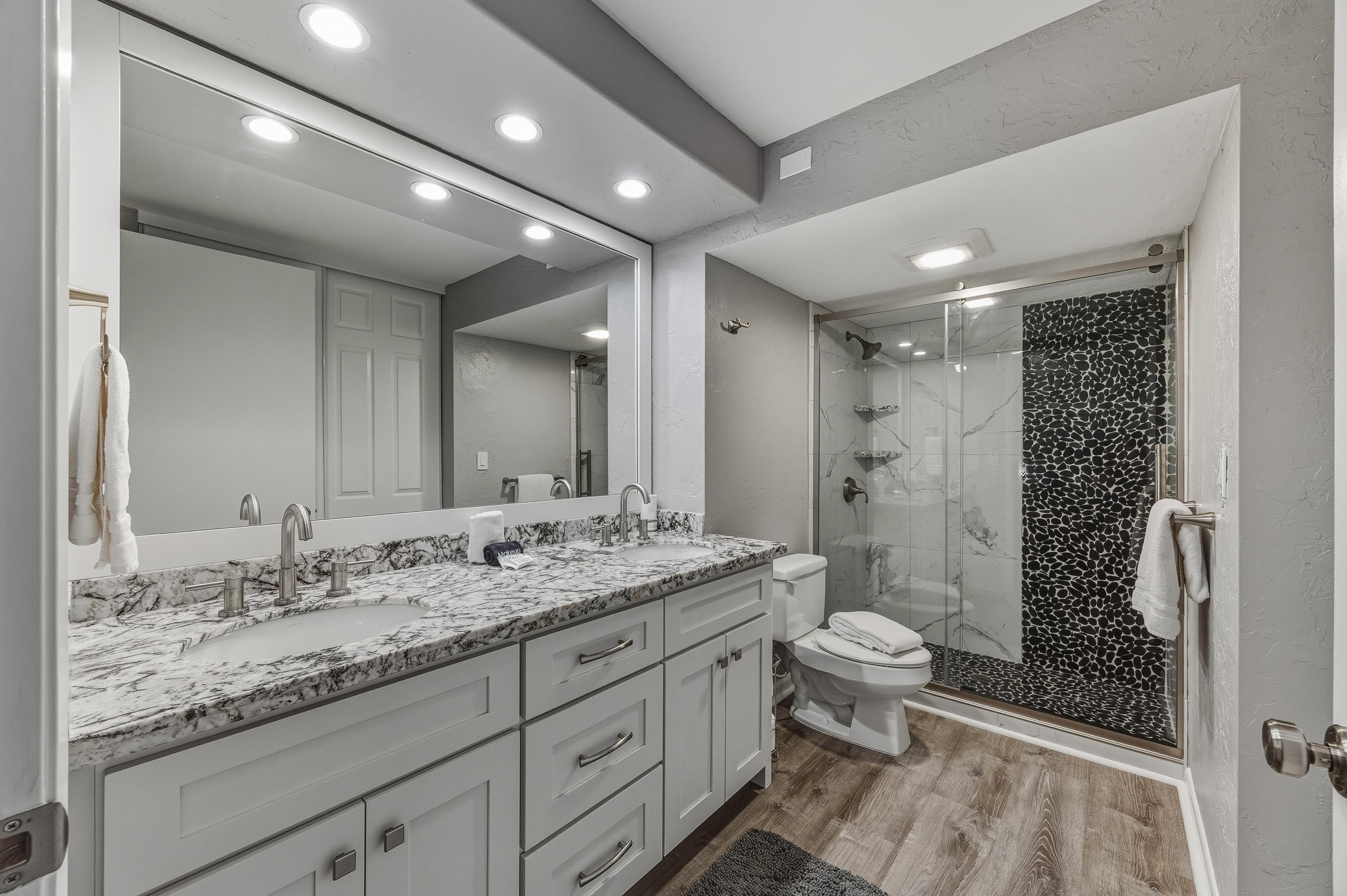 3543 Lower Honoapiilani Road, Unit H103 Lahaina, HI 96761 - Photo 29 of 50 a bathroom with a granite countertop sink a toilet a mirror and shower