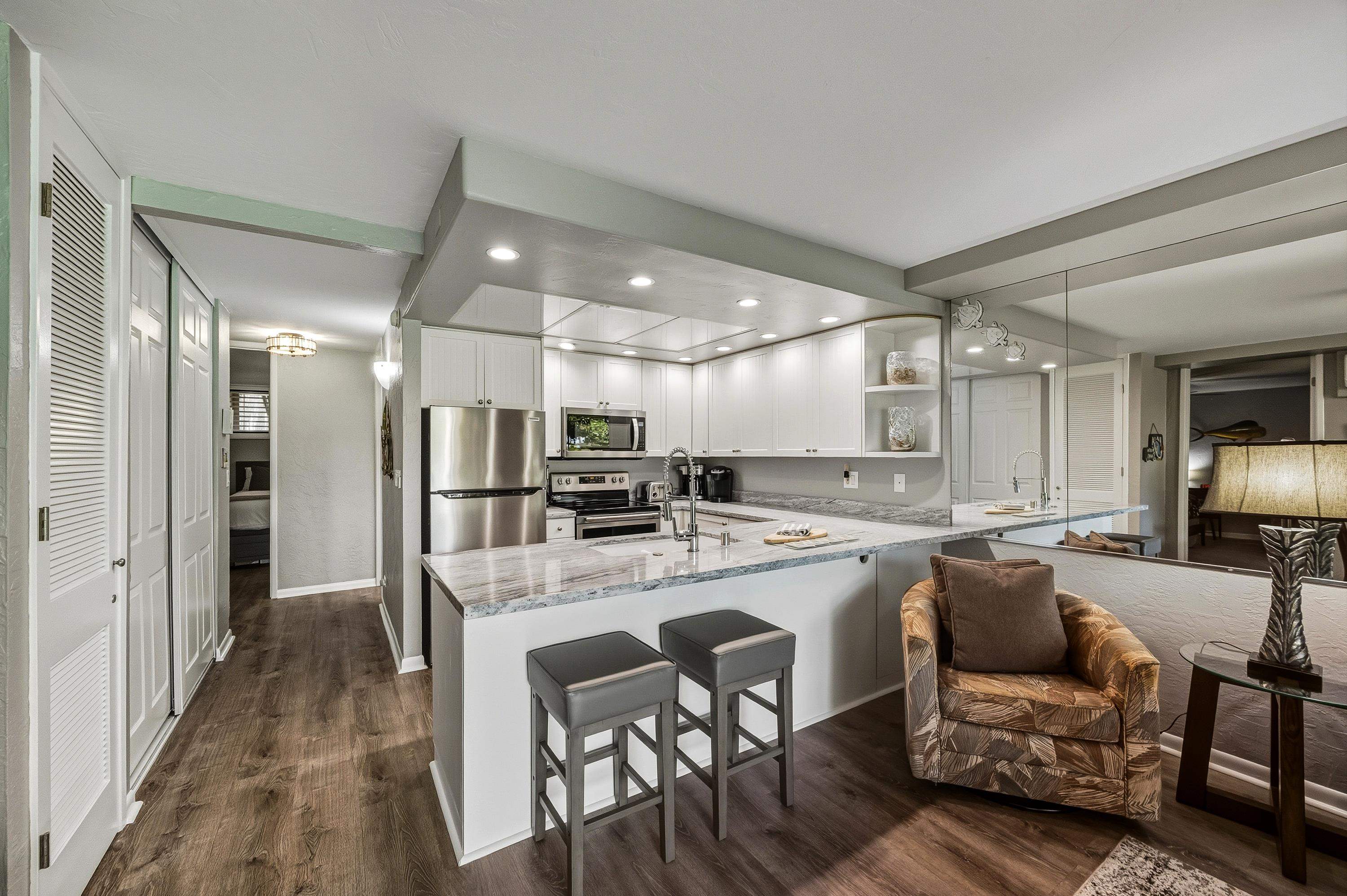3543 Lower Honoapiilani Road, Unit H103 Lahaina, HI 96761 - Photo 6 of 50 a kitchen with a dining table chairs refrigerator and microwave