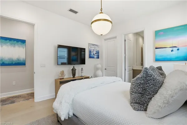 a bedroom with a bed and a flat tv screen on dresser