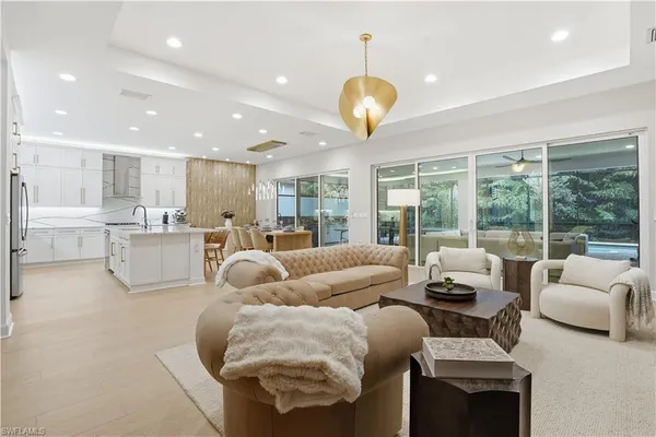 a living room with furniture and a large window with kitchen view