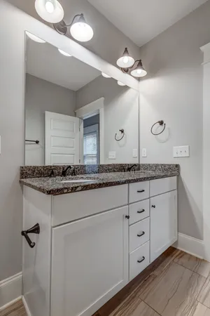a bathroom with a granite countertop double vanity sink and a mirror