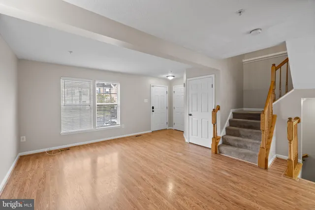 a view of an empty room with wooden floor and stairs