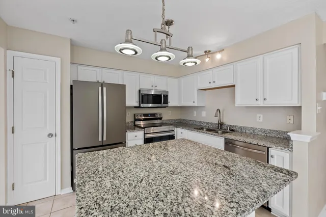 a kitchen with stainless steel appliances granite countertop a refrigerator a stove a sink dishwasher a refrigerator and white cabinets with wooden floor