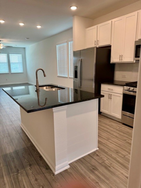 201 Betsy Road Hutto, TX 78634 - Photo 8 of 18 Kitchen featuring a central island with a sink and dark countertop, white cabinetry, and stainless steel appliances