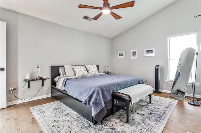 a bedroom with a bed a rug and wooden floor
