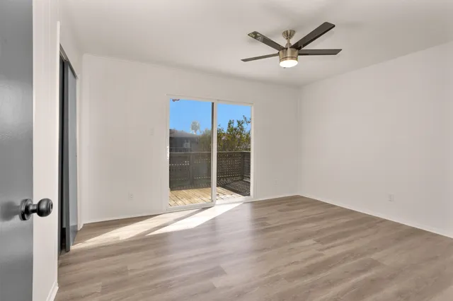 an empty room with wooden floor and ceiling fan