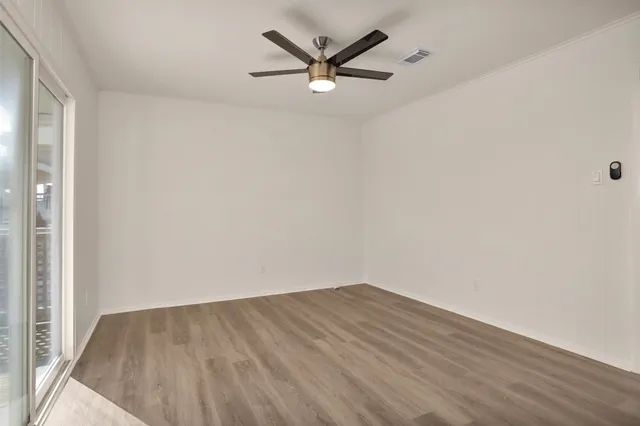 an empty room with a ceiling fan and wooden floor