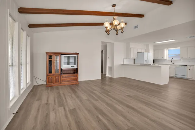 a view of a hallway with wooden floor and a kitchen