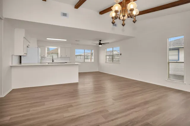 a view of an empty room with kitchen and window