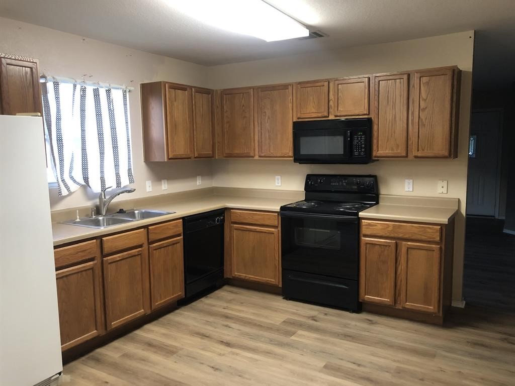 211 Woodley Road Leander, TX 78641 - Photo 2 of 15 Warm oak cabinetry pairs with vinyl plank flooring in this functional kitchen layout.