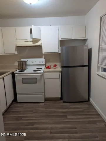 a kitchen with a stove a refrigerator and white cabinets