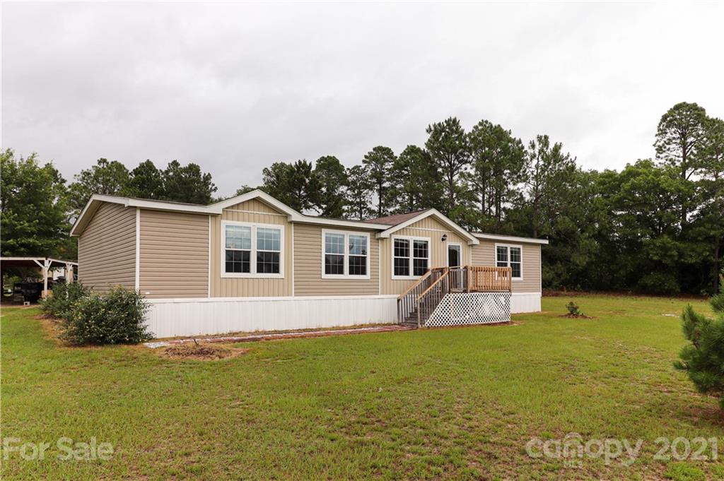 4024 Steen Road Mount Croghan, SC 29727 - Photo 2 of 37 a white house with a big yard and potted plants in front of it