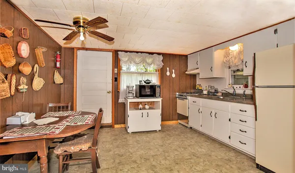 a kitchen with granite countertop a refrigerator a stove and white cabinets