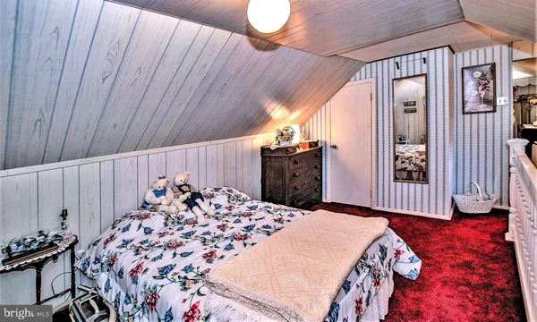 a bed sitting in a bedroom next to a window and a chair