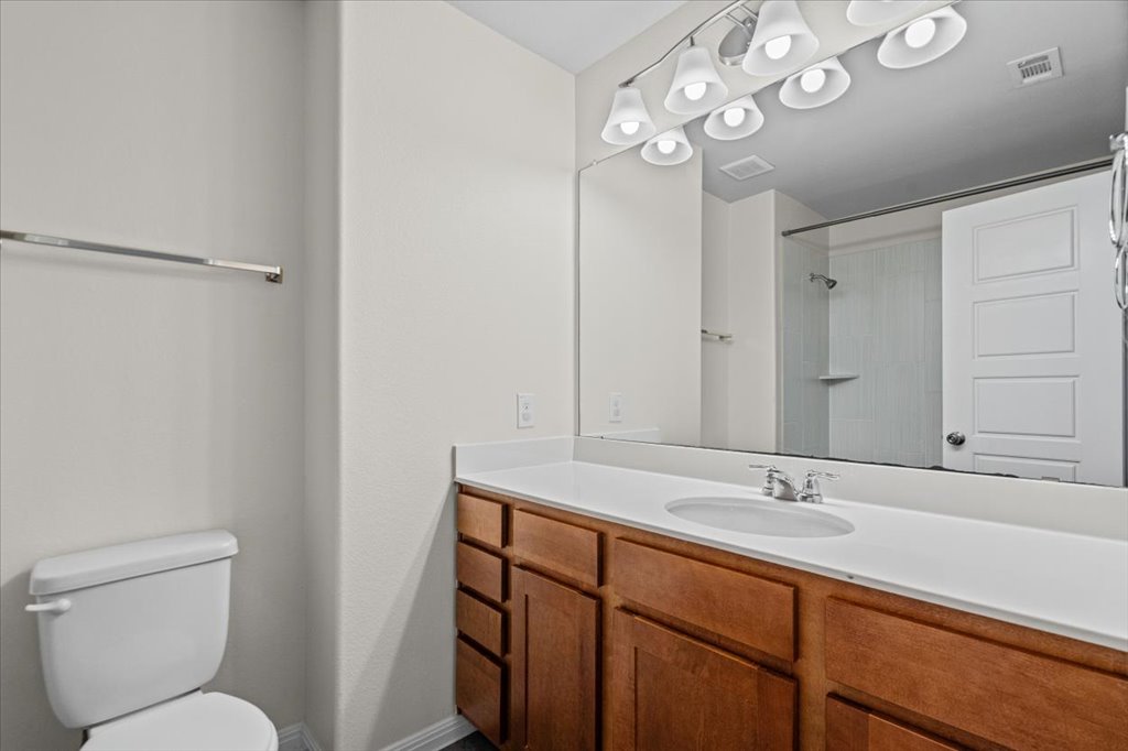 1502 Airedale Road, Unit 2502 Austin, TX 78748 - Photo 22 of 28 A well-lit primary bathroom features a single vanity, a sleek mirror, and a convenient toilet.