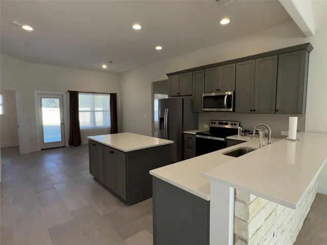 a kitchen with kitchen island a refrigerator sink and stove