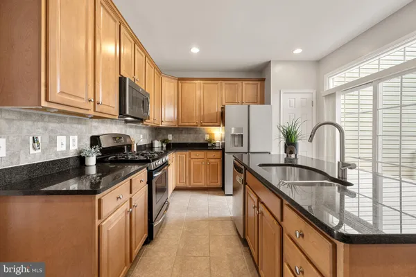 a kitchen with kitchen island granite countertop a stove a sink a refrigerator cabinets and a dining table