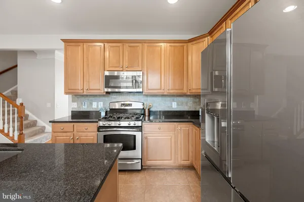 a kitchen with stainless steel appliances granite countertop a sink a stove and a refrigerator