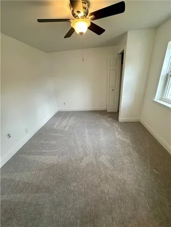 an empty room with a window and a fan
