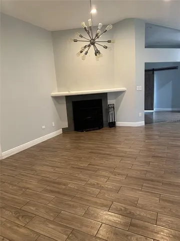 a view of an empty room with a ceiling fan and wooden floor