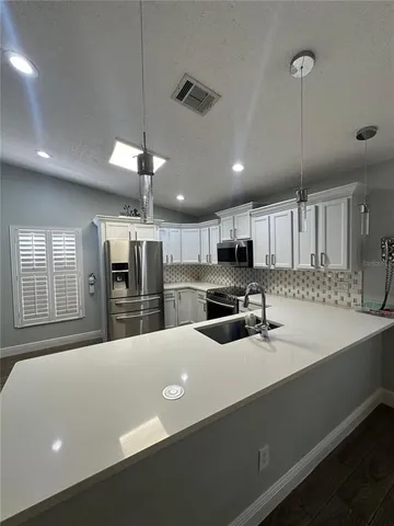 a kitchen with stainless steel appliances a sink a stove a refrigerator a center island a stove and a window