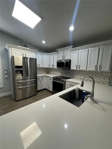a kitchen with granite countertop a refrigerator and a stove top oven