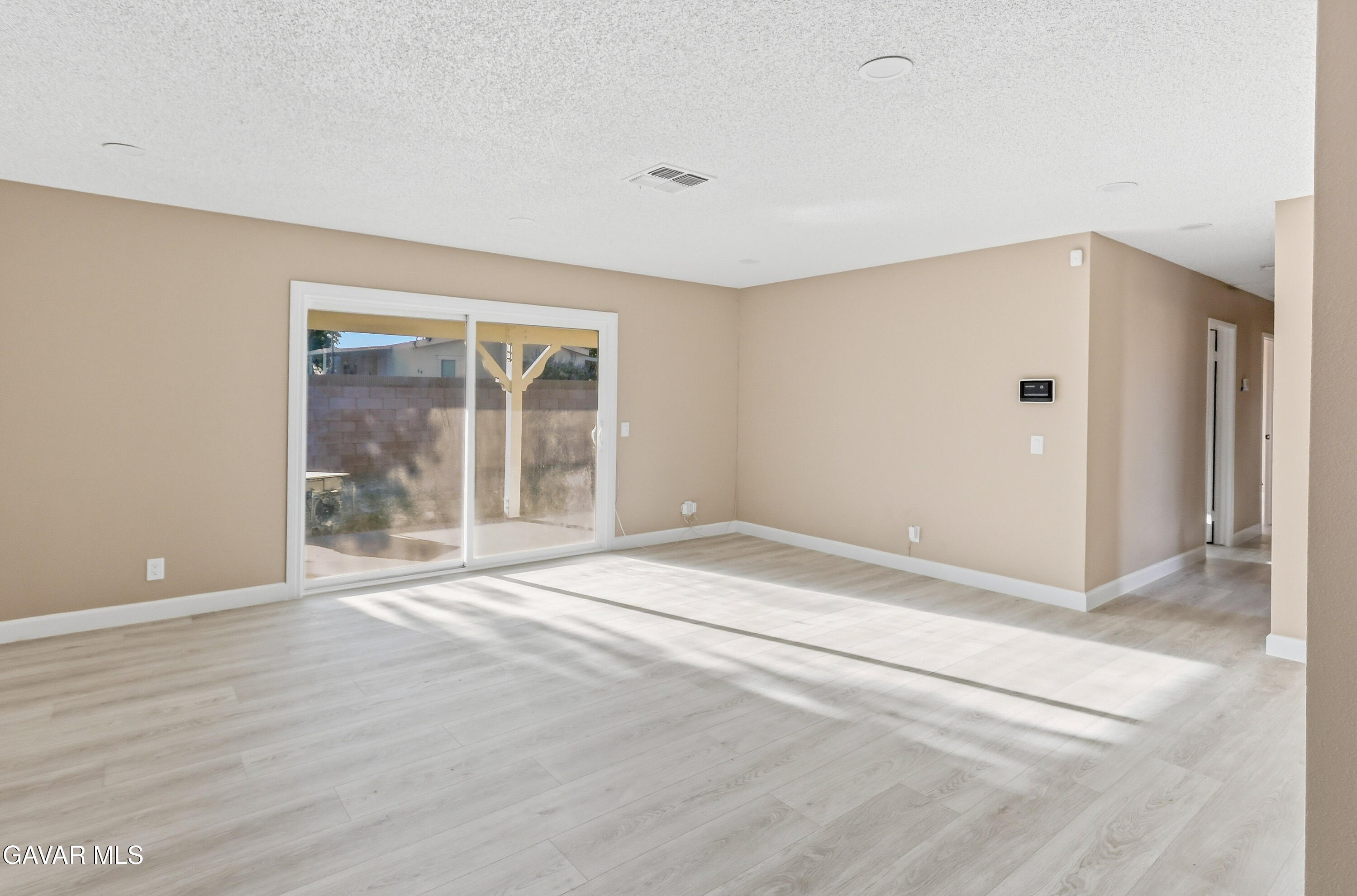 3340 West Roxbury Street Rosamond, CA 93560 - Photo 9 of 20 a view of an empty room with wooden floor and a window