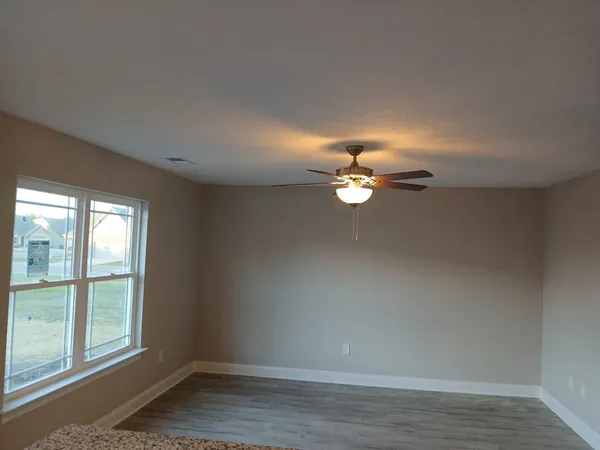 an empty room with a window and a fan
