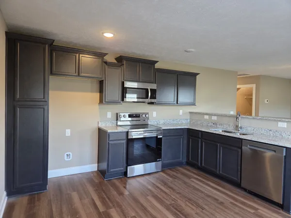 a large kitchen with stainless steel appliances granite countertop a sink and cabinets