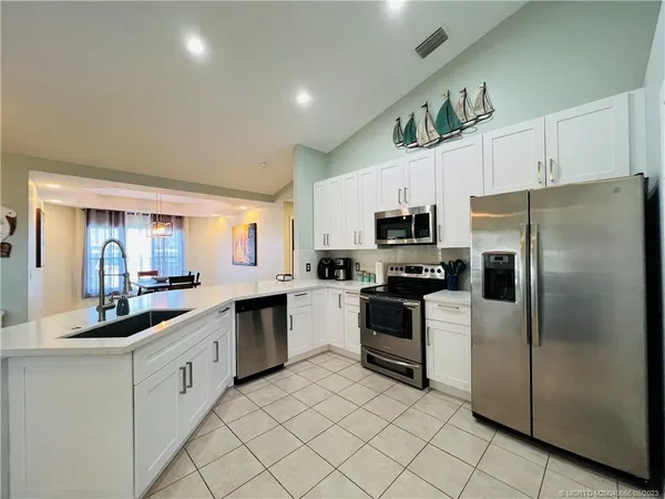 a kitchen with stainless steel appliances granite countertop white cabinets a sink a stove a microwave and a refrigerator