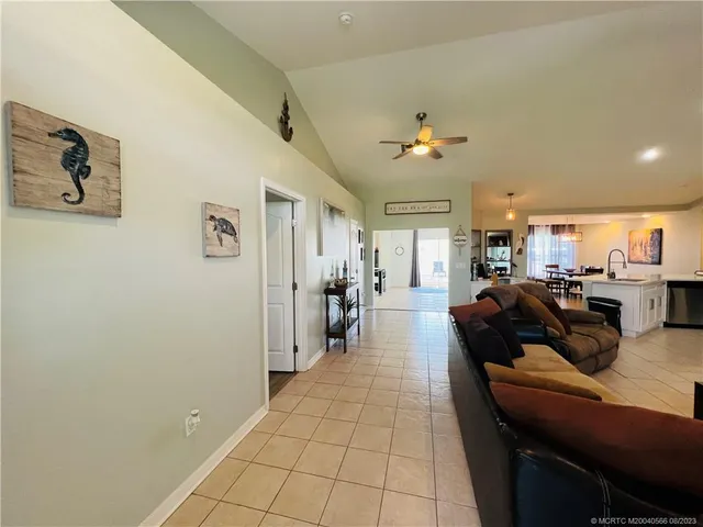 a living room with couches and kitchen view with wooden floor