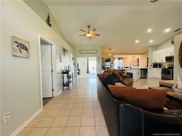 a living room with furniture a computer on a desk and kitchen view