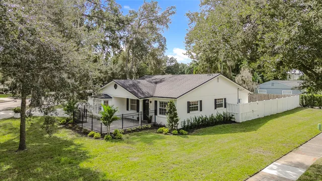 a view of a house with a yard potted plants and large tree
