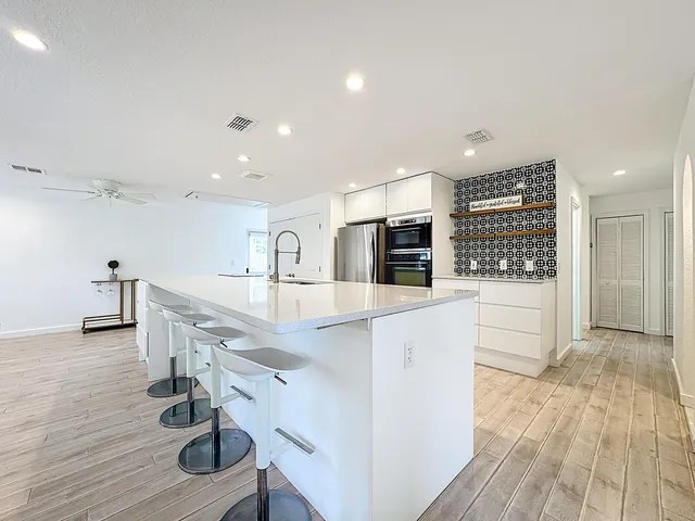 a large white kitchen with stainless steel appliances granite countertop a sink and dishwasher with wooden floor