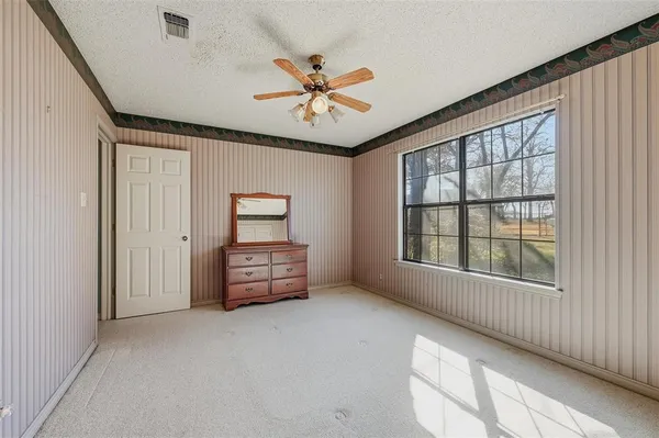 an empty room with windows and ceiling fan