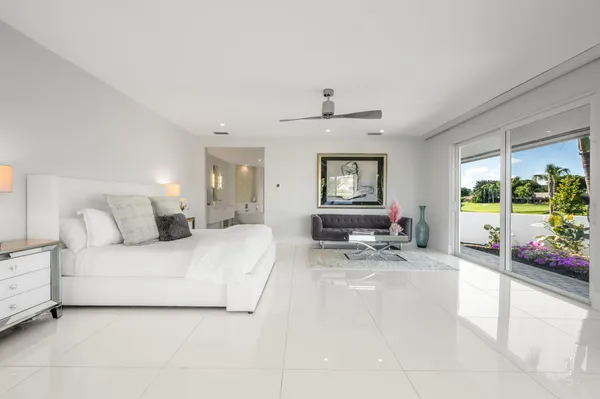 a spacious bedroom with a bed a large window with table and chairs