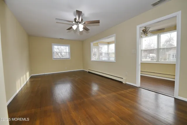 a view of an empty room with wooden floor and a window