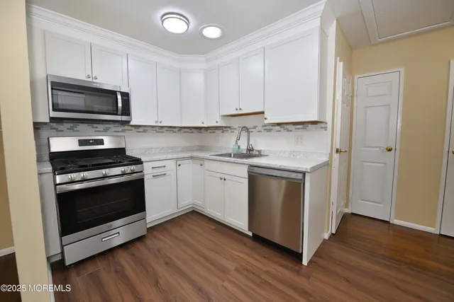 a kitchen with stainless steel appliances white cabinets a sink and a stove