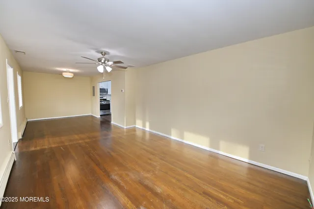 an empty room with wooden floor and chandelier fan