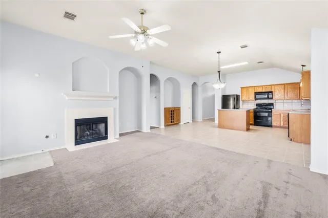 an empty room with a fireplace and chandelier fan
