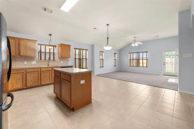 a large kitchen with kitchen island granite countertop a stove a sink a window and a counter top space