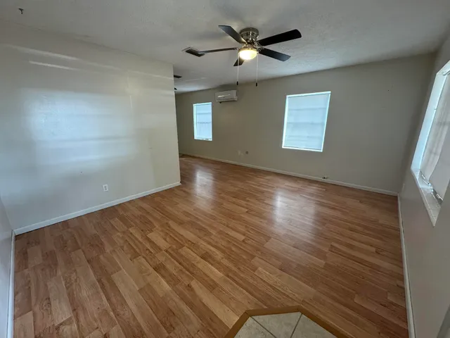 a view of empty room with wooden floor and fan