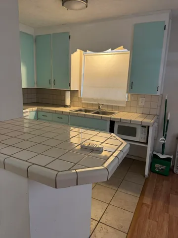 a view of a kitchen with kitchen island a sink wooden floor and a counter top space