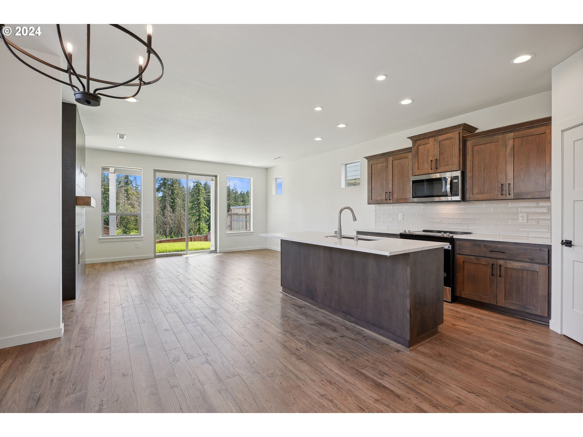 2541 South White Salmon Drive Ridgefield, WA 98642 - Photo 5 of 29 a open kitchen with granite countertop a stove top oven a sink dishwasher a microwave oven and a dining table with wooden floor