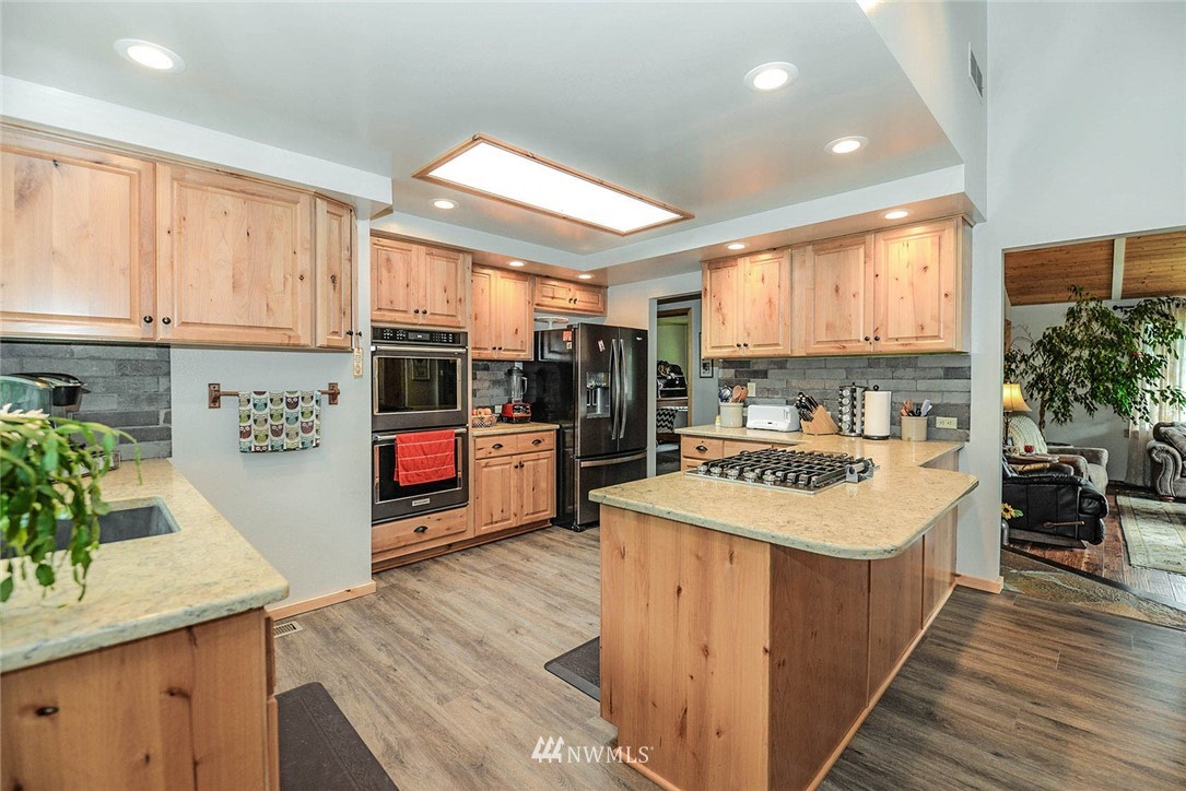 20431 Welch Road Snohomish, WA 98296 - Photo 6 of 25 a large kitchen with stainless steel appliances kitchen island a large counter top a stove a chimney a sink and cabinets