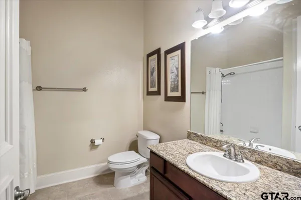 a bathroom with a granite countertop sink toilet a mirror a vanity and shower