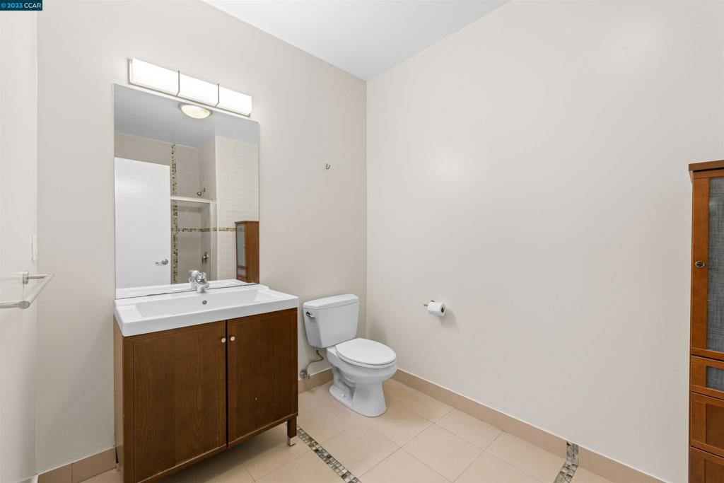 2300 Broadway Oakland, CA 94612 - Photo 18 of 32 a bathroom with a sink a toilet and mirror