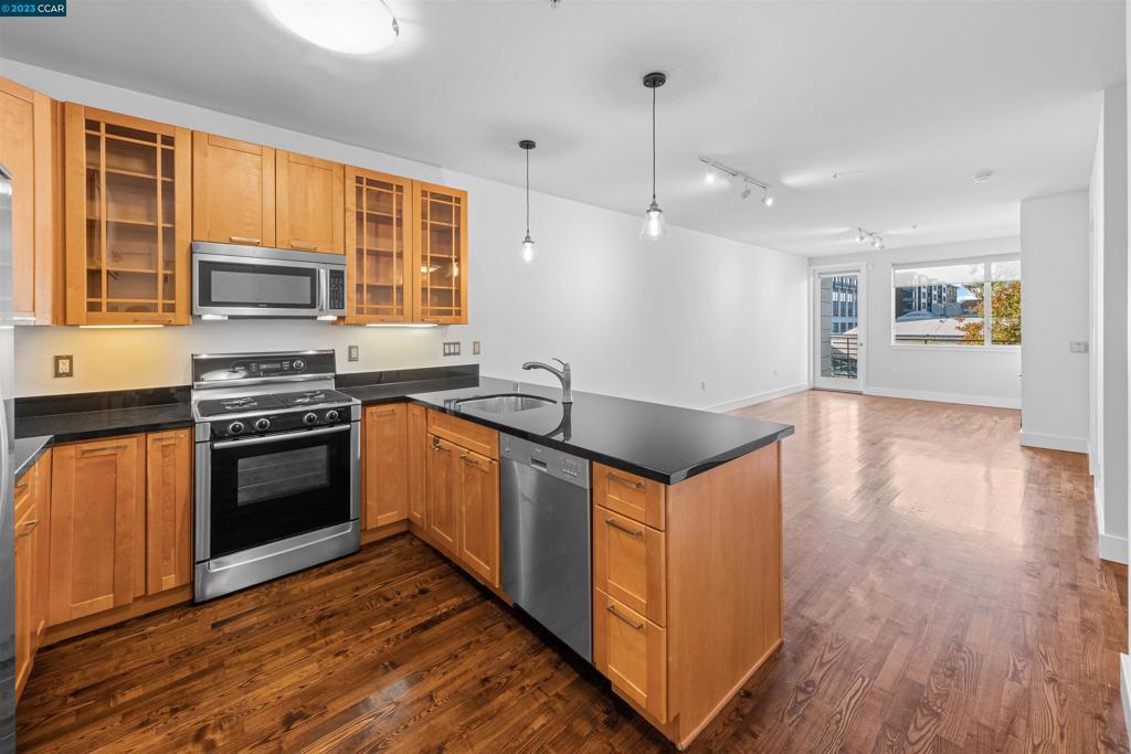 2300 Broadway Oakland, CA 94612 - Photo 6 of 32 a kitchen with stainless steel appliances granite countertop a stove a sink and a microwave