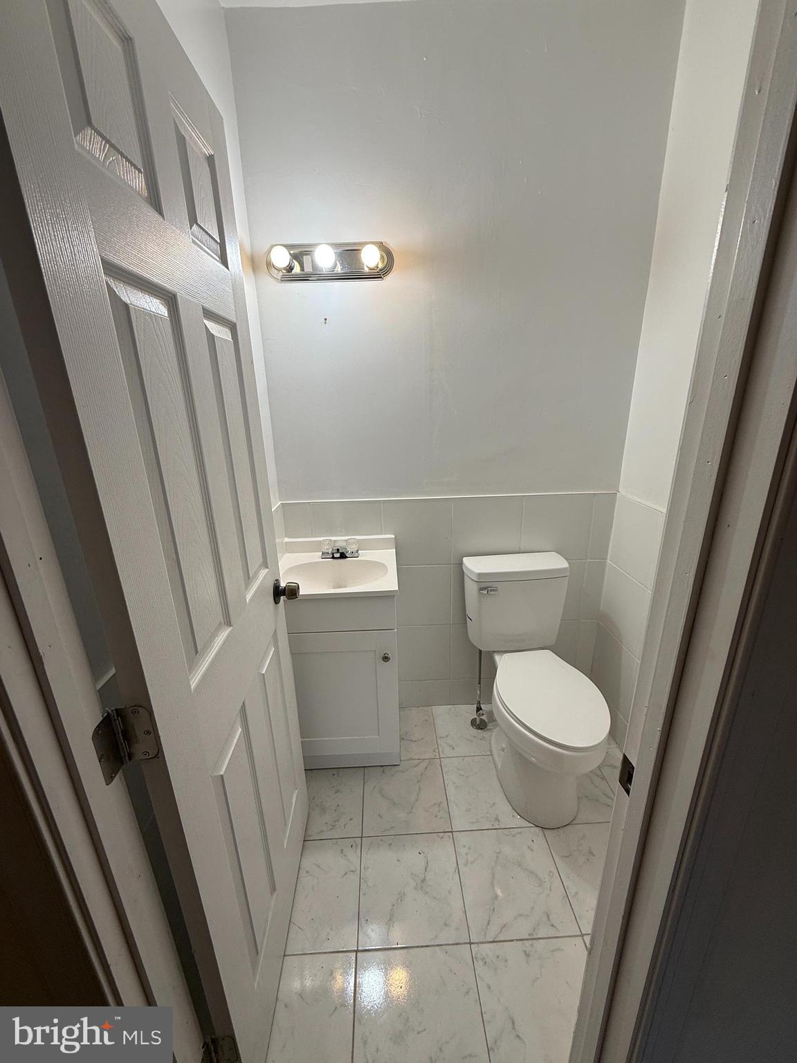 3309 Brighton Street Baltimore, MD 21216 - Photo 17 of 32 a white toilet sitting next to a white sink and vanity